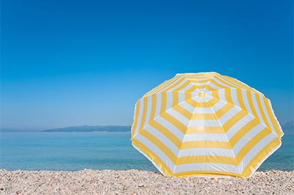 iStock_000008418783 image of a yellow and white stripes umbrella on the beach